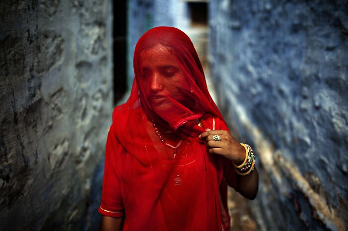 Woman in red veil with bangles walking in narrow alley, best pics Siena International Photo Awards 2026