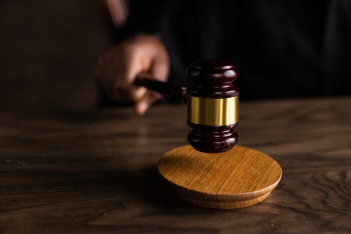 A wooden judge gavel striking a sound block during a legal proceeding. A wooden judge gavel striking a sound block during a legal proceeding.