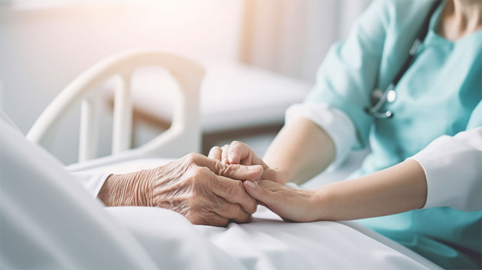 Caregiver holding the hand of a senior patient during comforting end-of-life conversations. Caregiver holding the hand of a senior patient during comforting end-of-life conversations.