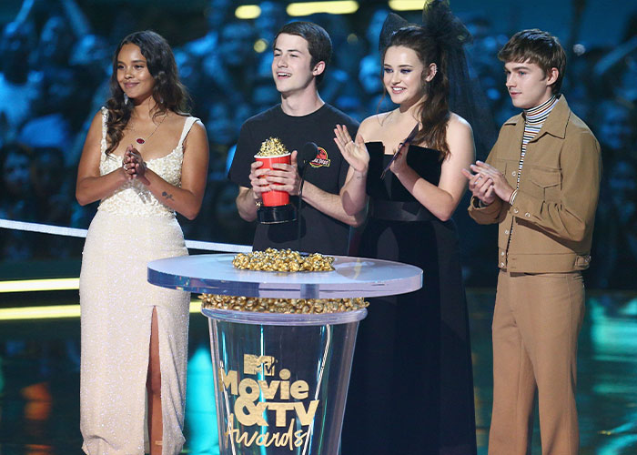 Hollywood actress Katherine Langford on stage with her co-stars at an awards show.