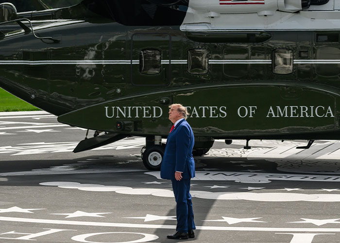 Donald Trump standing on a helipad beside Marine One, showing Trump waving at nobody from a distance. Donald Trump standing on a helipad beside Marine One, showing Trump waving at nobody from a distance.