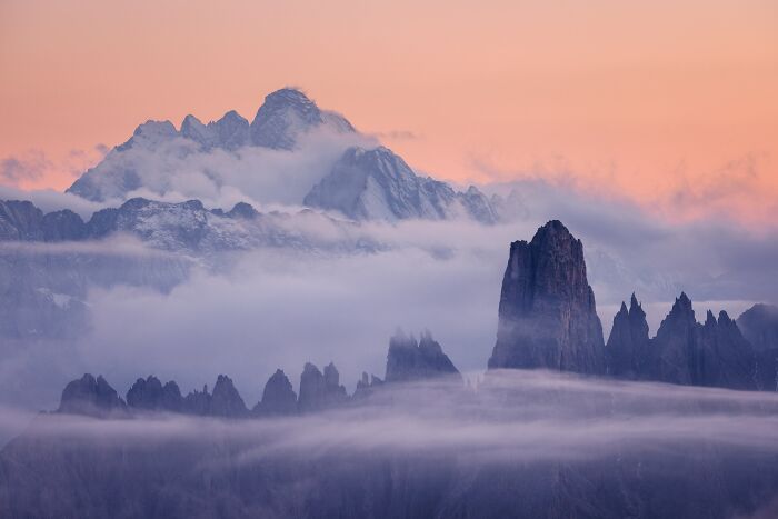 Jagged mountain peaks rising above low clouds at sunset in Natural Landscape Photography Awards 2026.