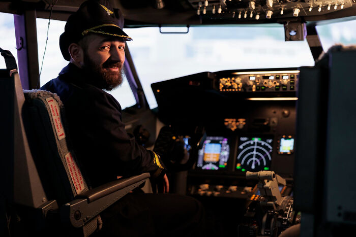 A smiling airplane pilot sitting inside a cockpit, relating to obvious lies told in professional settings