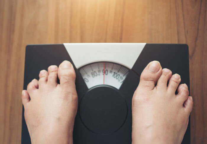 Top-down view of feet standing on a weight scale, symbolizing hilariously obvious lies about weight loss