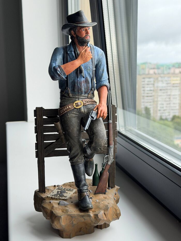 A highly detailed Arthur Morgan figurine made with 3D prints standing by a window.