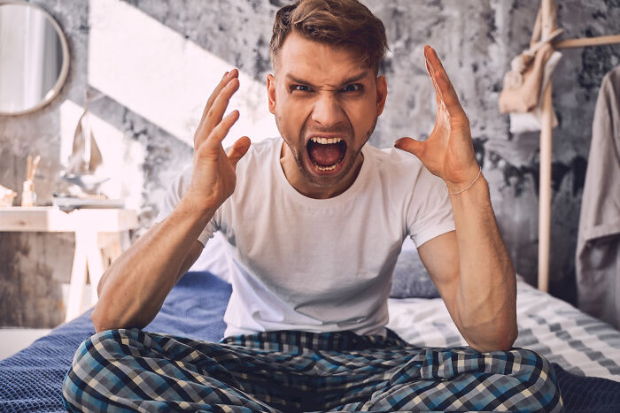 An angry man yelling frantically on his bed, illustrating the emotional toll of divorce stories.