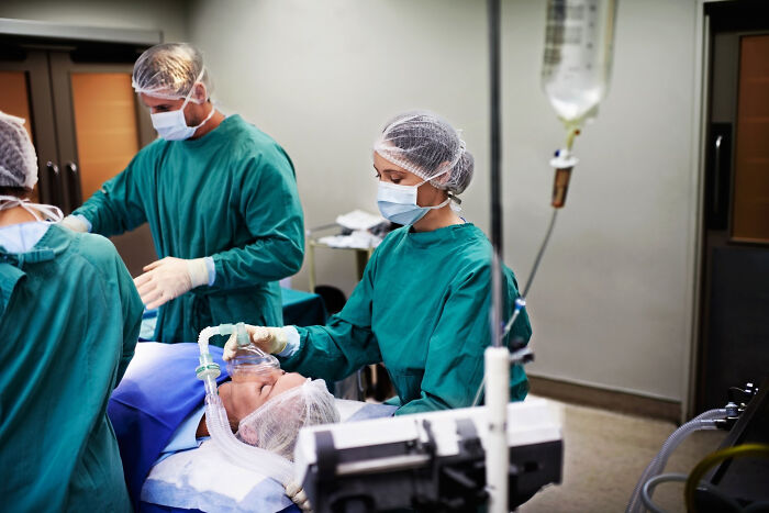 Healthcare workers performing a medical procedure with an oxygen mask in surgery