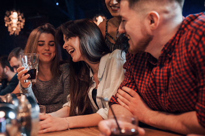 Happy coworkers gathered at a bar celebrating after a bad boss gets demoted.