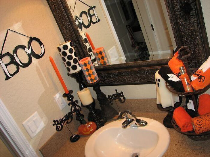 Spooky Halloween home decorations featuring orange and black towels and candle holders.