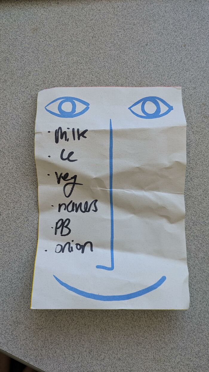A piece of found paper with a handwritten grocery list drawn as a face with blue eyes and a smile.