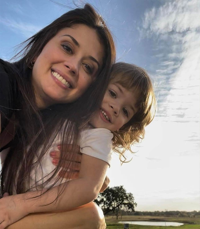 A happy mom smiling with her young daughter outdoors during happier times A happy mom smiling with her young daughter outdoors during happier times