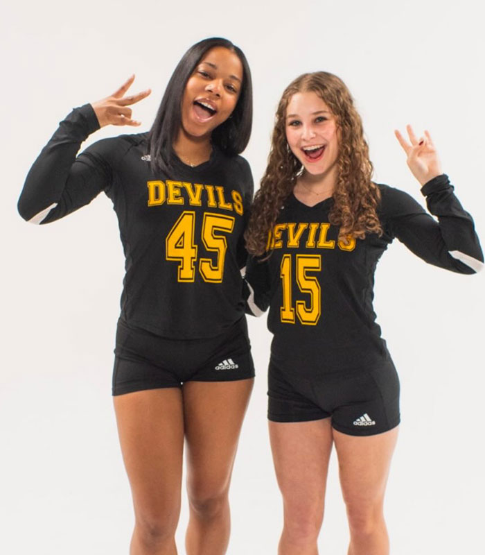 Two Arizona State cheerleader teammates posing together in their uniforms.