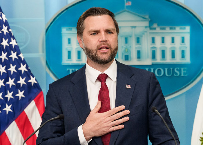JD Vance standing at a podium in front of a White House backdrop. JD Vance standing at a podium in front of a White House backdrop.
