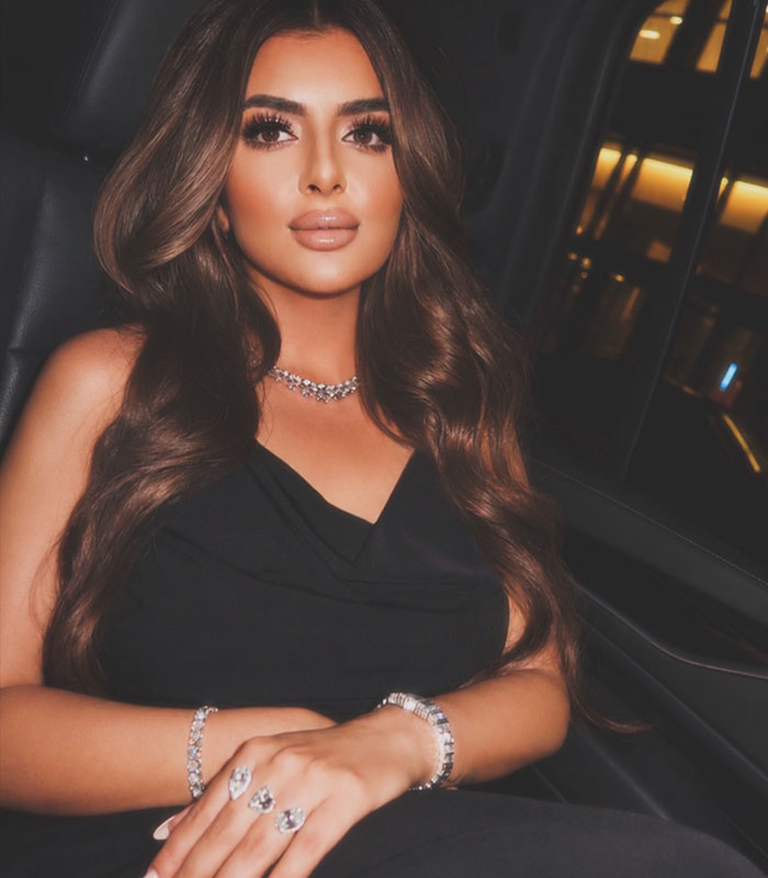 Royal mother wearing elegant jewelry and black dress in car interior