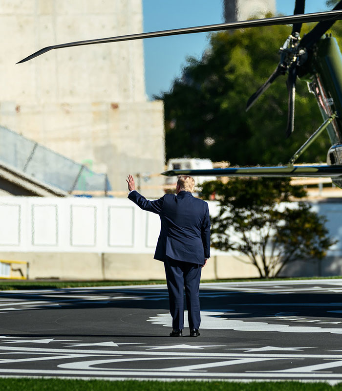 Back view of Donald Trump waving at nobody while standing on a helipad near a helicopter. Back view of Donald Trump waving at nobody while standing on a helipad near a helicopter.
