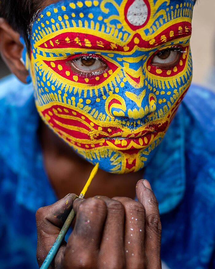 A detailed close up of a face painted in yellow and blue, showcasing the beauty of human expression in portrait photos.