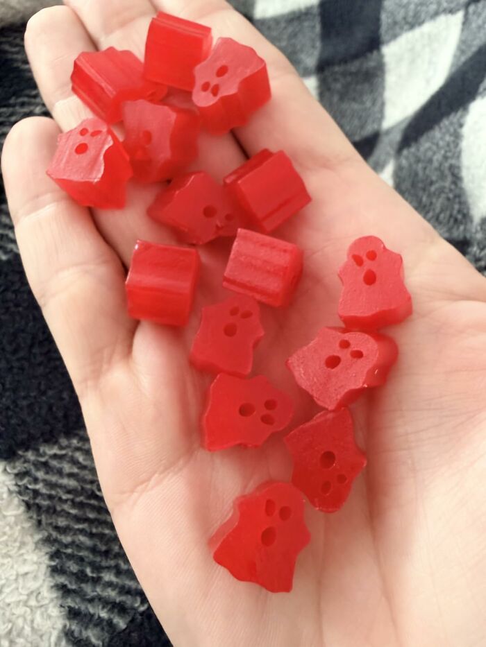 A hand holding red ghost-shaped candies, fitting for the best Halloween candies selection.