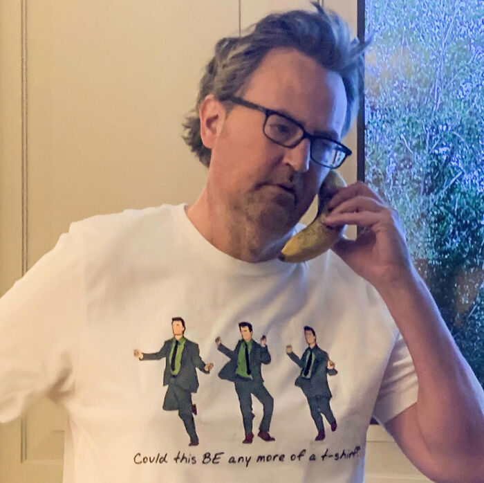 Late actor Matthew Perry wearing a Friends themed t-shirt while holding a banana to his ear like a phone.