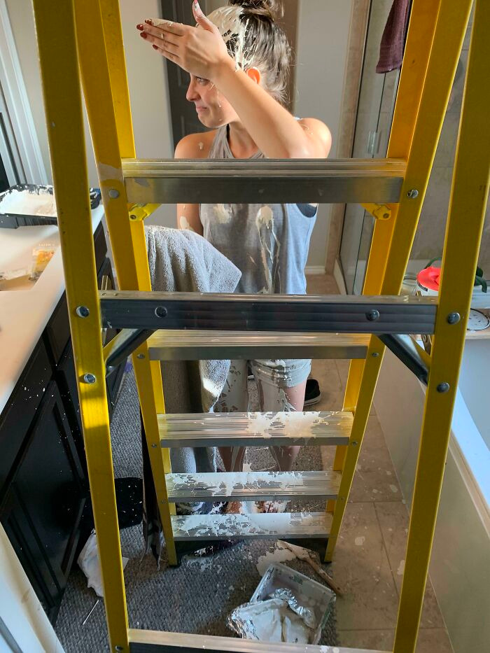 A woman covered in white paint during a DIY project gone wrong, showing a home renovate fiasco