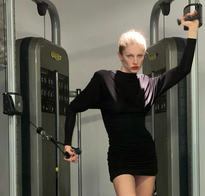 Trans actress working out in a gym wearing a black dress