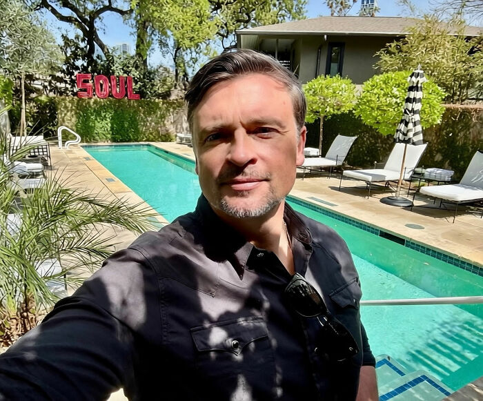 Selfie of TV star Tom Welling outdoors near a swimming pool, posing casually after social media frenzy.