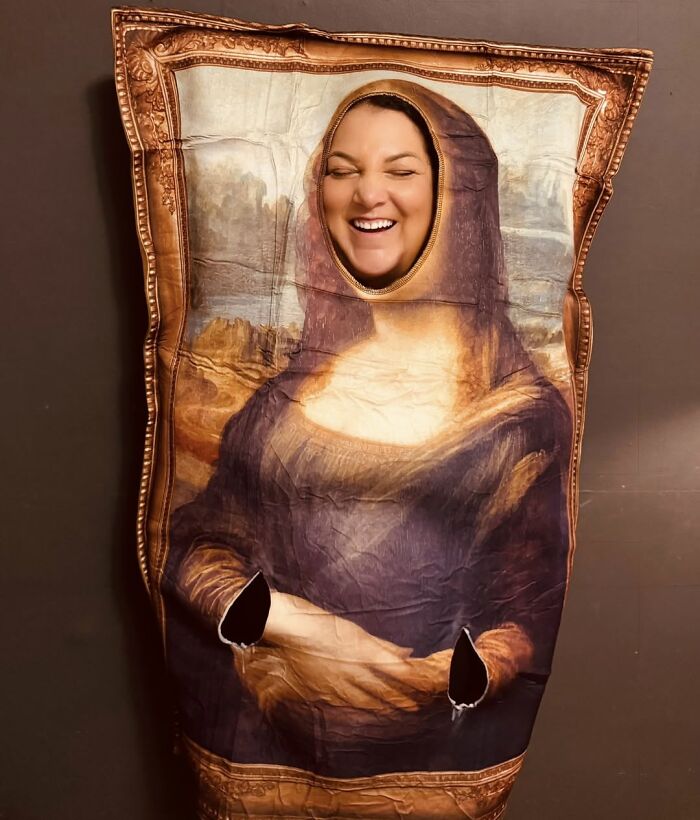 A smiling woman wearing a funny Mona Lisa painting outfit as a low-effort Halloween costume.