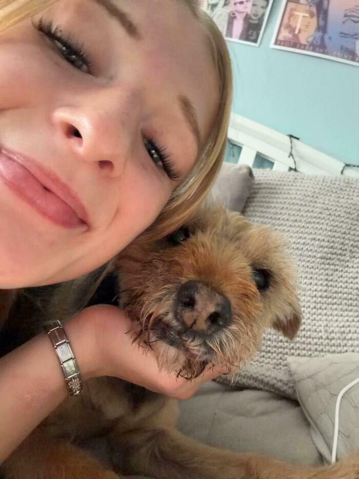 A girl smiling while holding her scruffy brown dog close, sharing life stories with pets