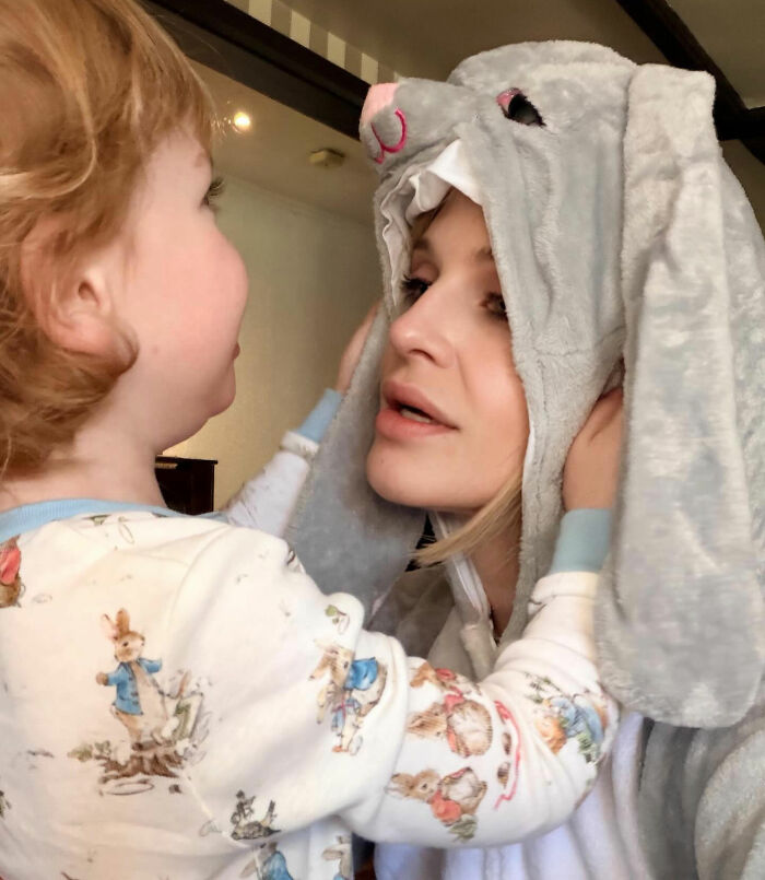 Kelly Osbourne wearing a bunny costume hood while interacting with a young child.