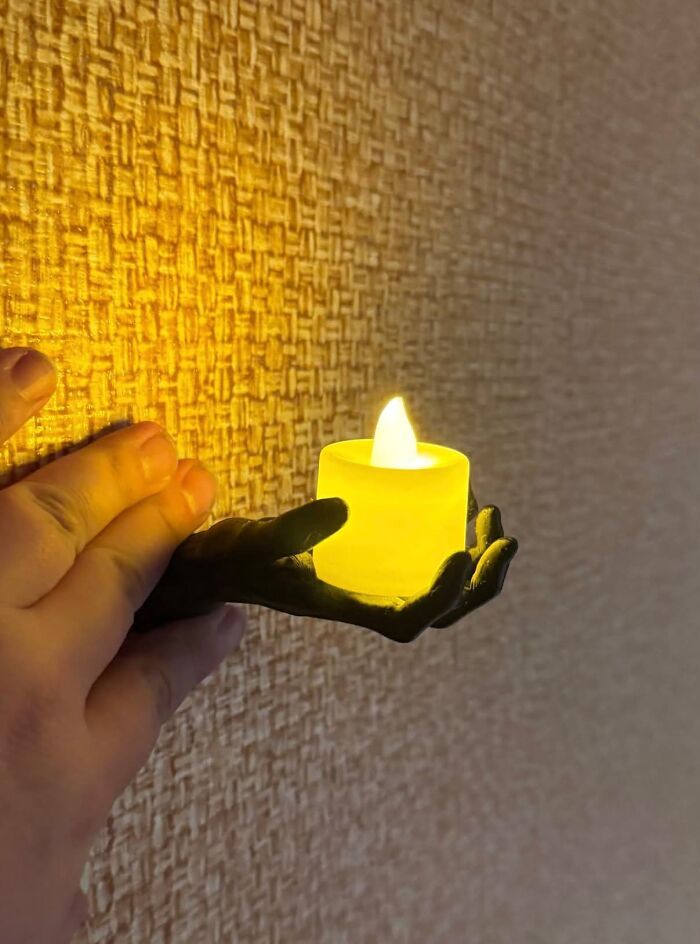 Hand-shaped wall mount with a small yellow LED candle, showing clever 3D prints.
