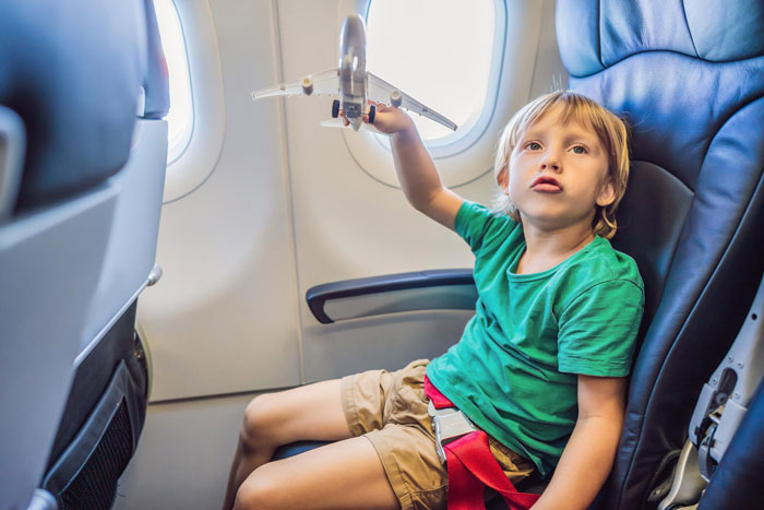 Young child sitting in an airplane seat playing with a toy plane, representing the child involved in a diverted flight. Young child sitting in an airplane seat playing with a toy plane, representing the child involved in a diverted flight.