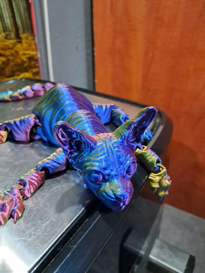 A colorful, iridescent 3D printed model of a hairless Sphynx cat with jointed limbs.