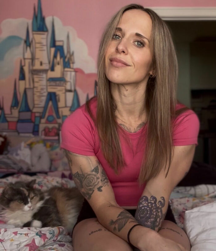Mom sitting in a room with a castle mural on the wall and a cat nearby, following controversy with her daughter school.