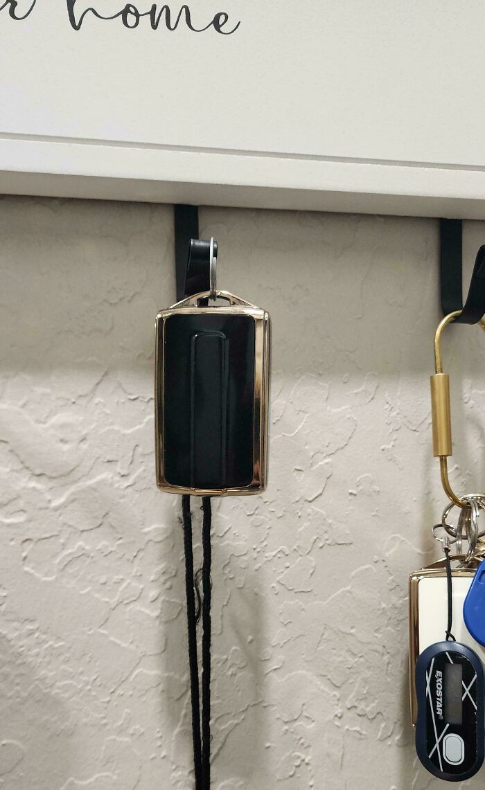 Husband funny quirk of hanging a small car key fob neatly on a wall hook designed for larger keys.