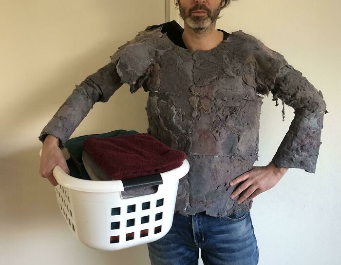 A funny DIY project of a man wearing a shirt completely made of grey dryer lint while holding a laundry basket