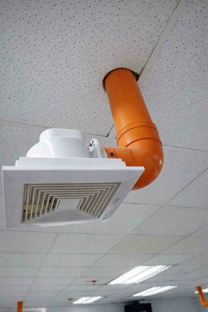 An unusual DIY project showing a bathroom exhaust fan connected to an orange pipe coming down from the ceiling