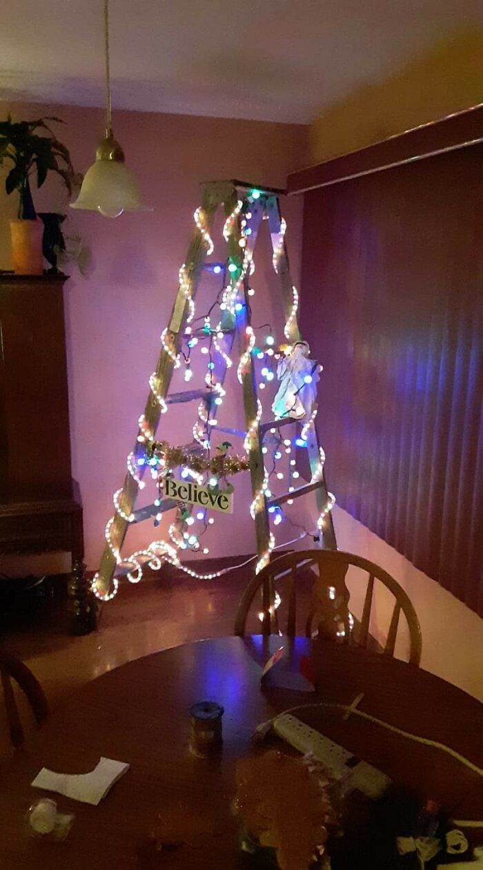 A creative DIY project of a wooden ladder decorated with shining colorful Christmas lights in a living room