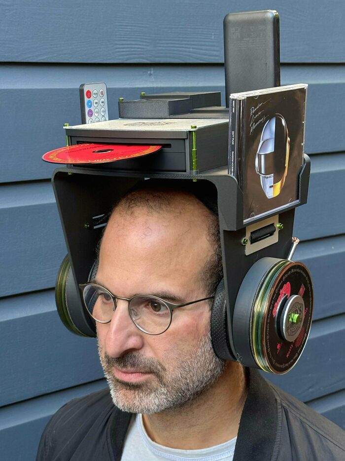 A man wearing a bizarre DIY project headset constructed with CD players and CDs.