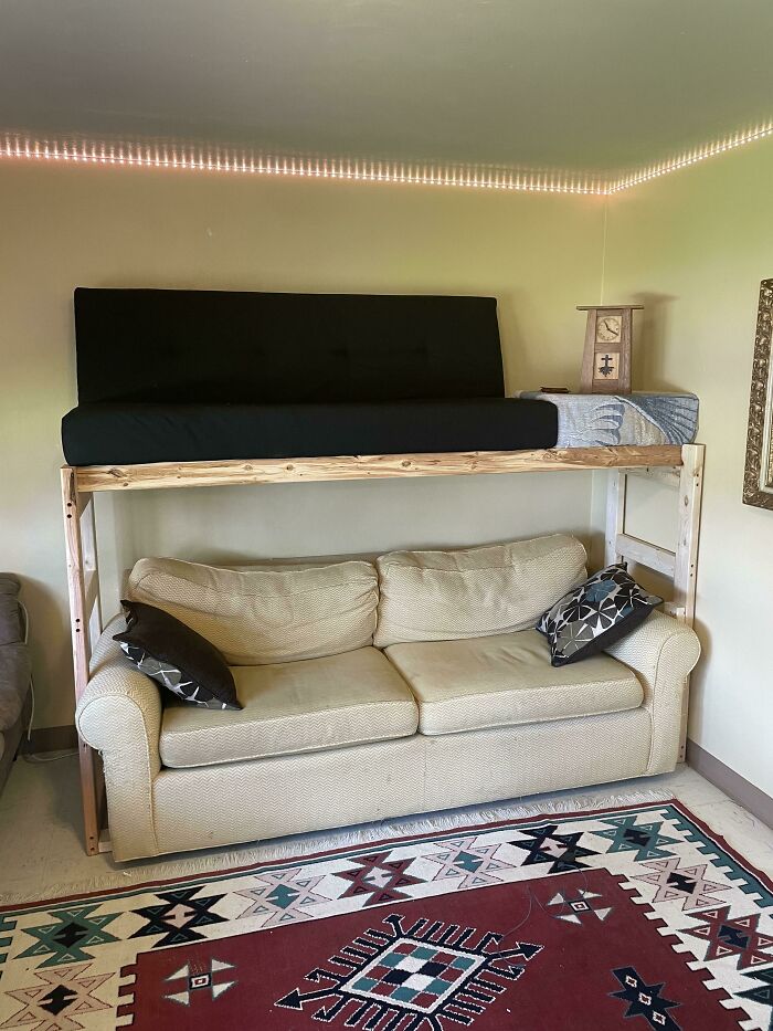 A custom wooden loft bed built over a beige sofa as part of home DIY projects.