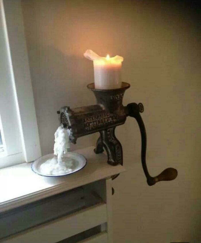 A white candle placed inside a vintage metal meat grinder for creative DIY projects
