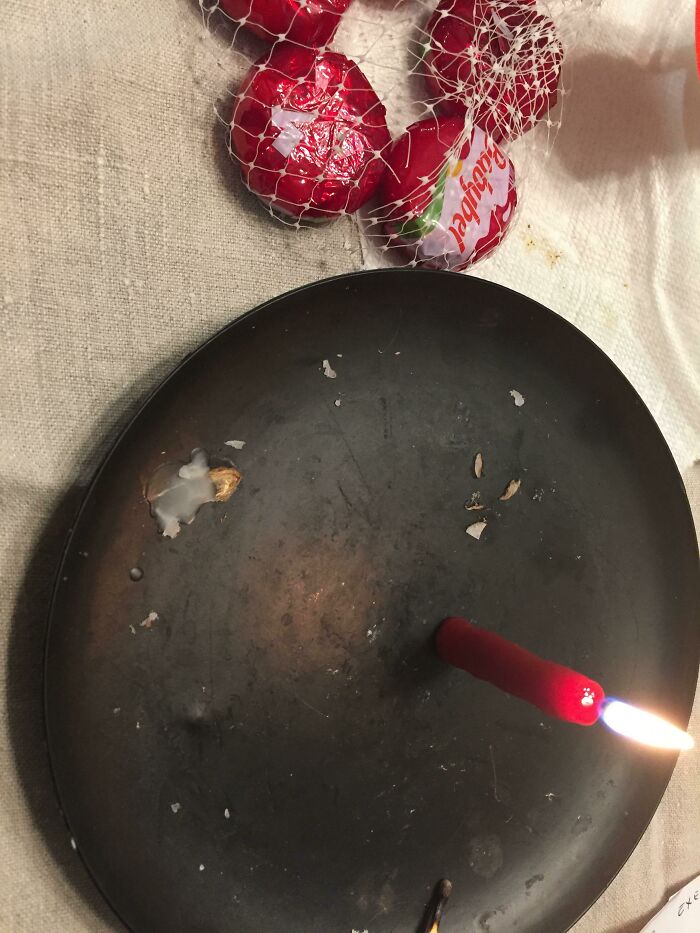 A small red candle burning on a dark plate near wax shells in unique DIY projects