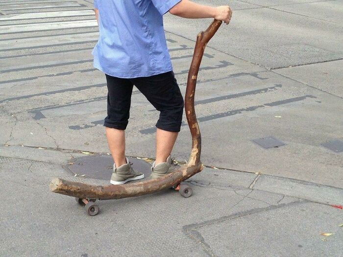 A creative DIY project of a homemade kick scooter made from a thick tree branch on a city street