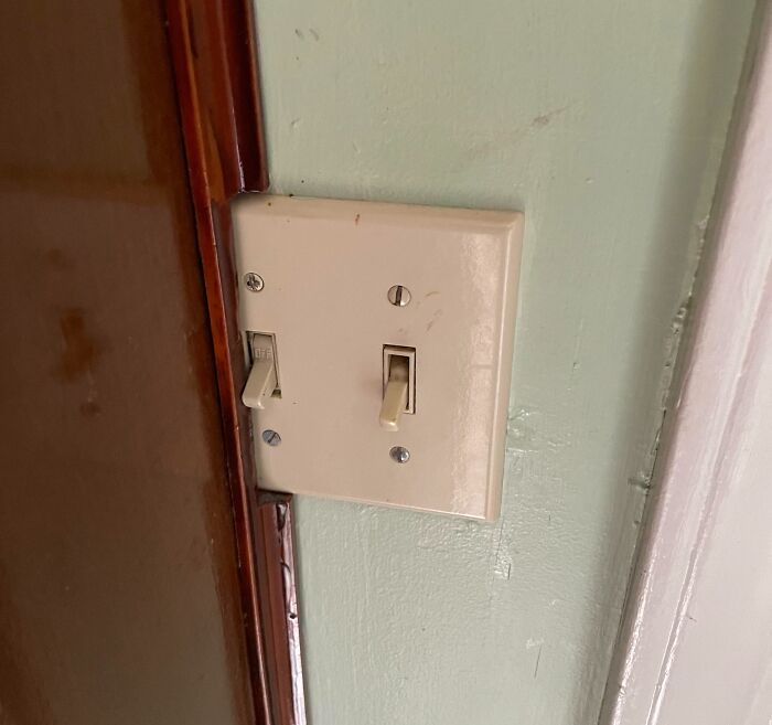 A light switch plate awkwardly cut into a door frame, illustrating DIY projects.