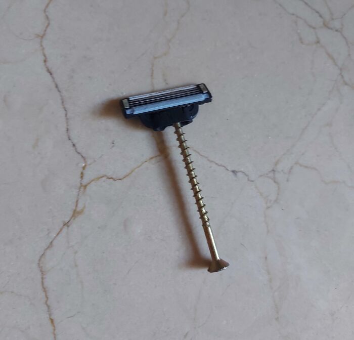 Razor blade head attached to a s***w as a makeshift razor handle, an unusual DIY project.