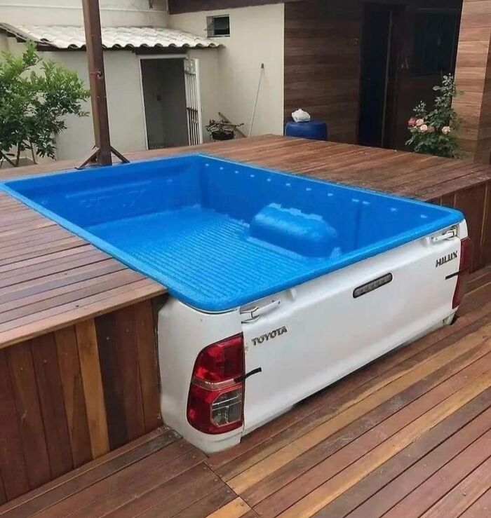 A unique DIY project featuring a white truck bed repurposed into a blue outdoor swimming pool on a wooden deck