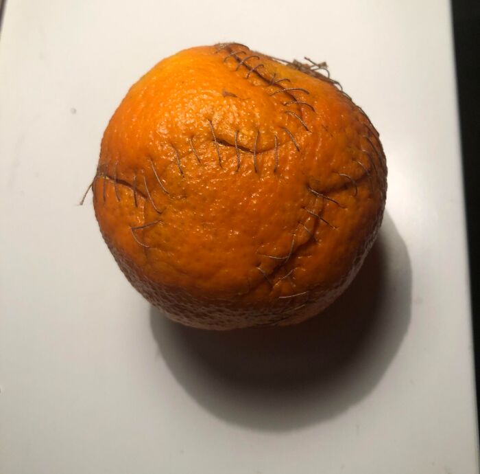 A tangerine with stitched surgical thread on its peel showing unusual DIY projects