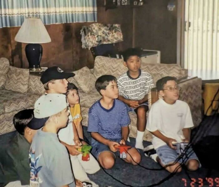Group of boys playing video games together in a living room, a scene filled with childhood nostalgia.