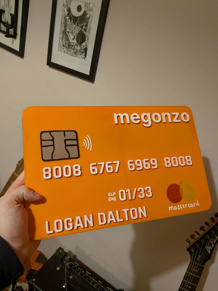 A hand holding a giant orange credit card, showcasing 3D prints made for unique, custom needs.