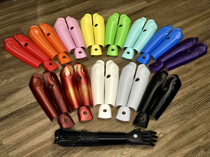 Multiple colorful 3D prints prosthetic arm covers arranged in a semi-circle.