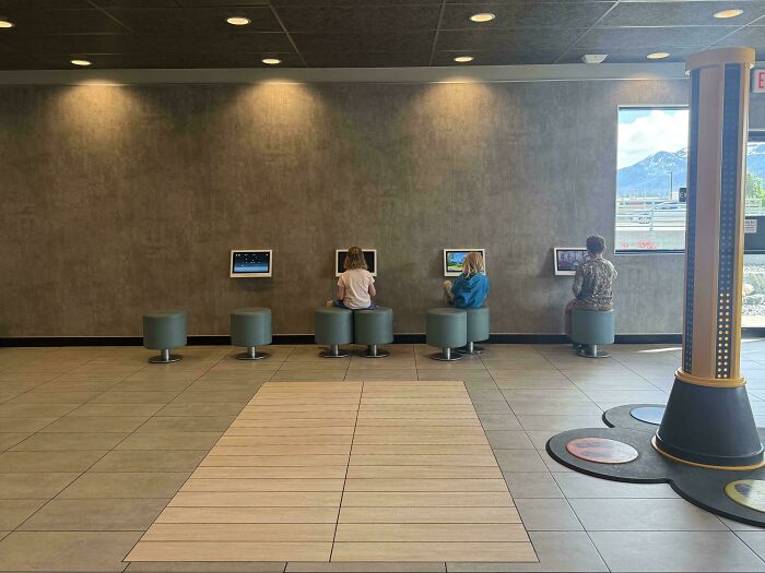 Children sitting on stools looking at tablets in a fast food restaurant, representing modern life in America.