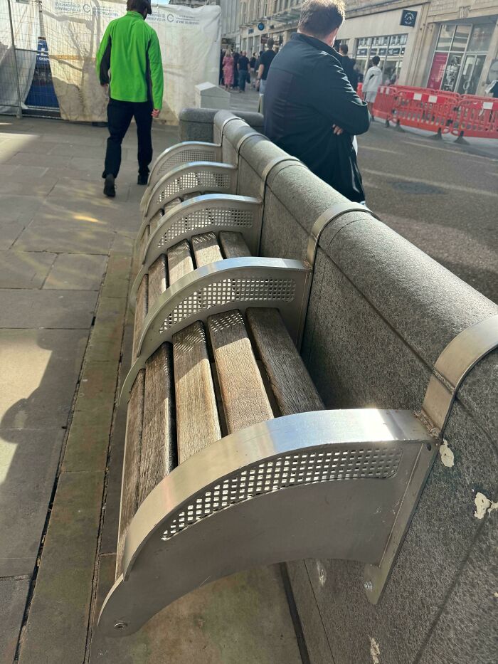 An uncomfortable bench designed to discourage lying down, highlighting aspects of modern life in America.
